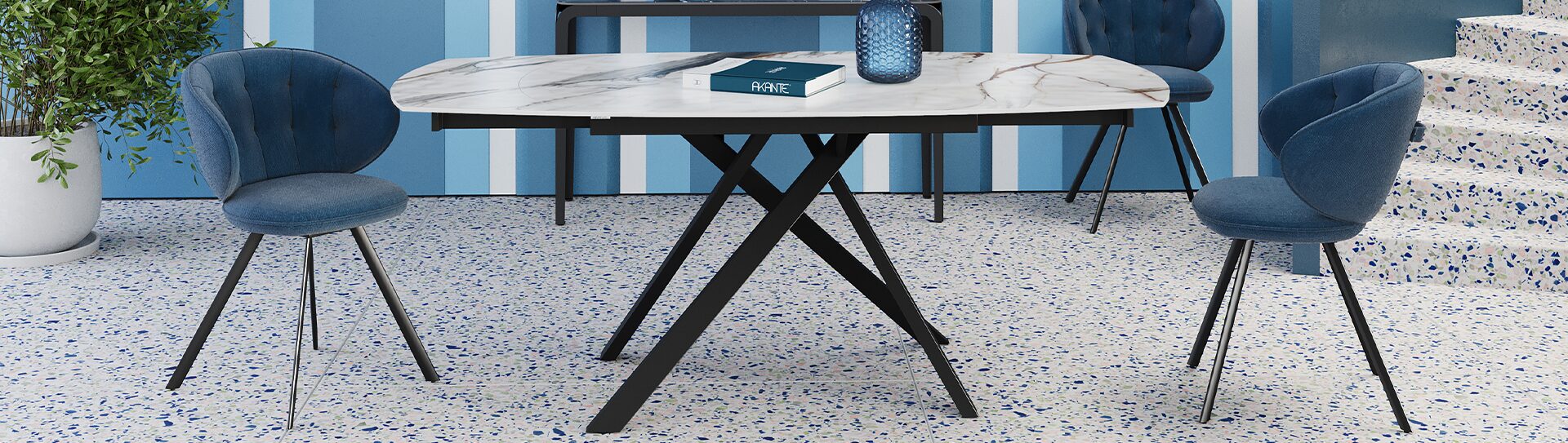 Table à manger STROMBOLI Table de repas STROMBOLI de forme rectangulaire avec un effet marbre et des quatre pieds noirs rigides dans un salon bleu avec un verre et un livre bleu sur la table l Géant du Meuble