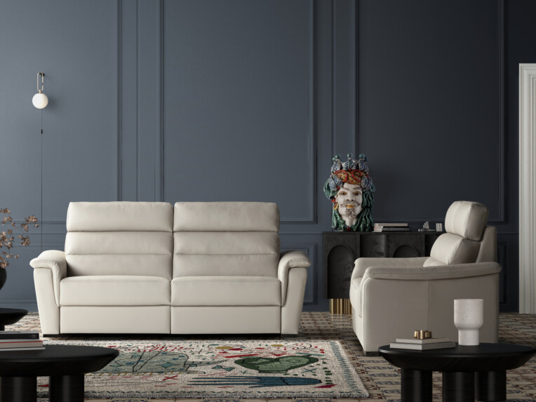 Salon élégant avec canapé et fauteuil en cuir beige, murs bleu foncé moulurés et tapis décoratif coloré. L’ensemble est complété par des tables basses noires et une console ornée d’un buste artistique.
canape-droit-vulcano-modele-le-geant-du-meuble.jpg