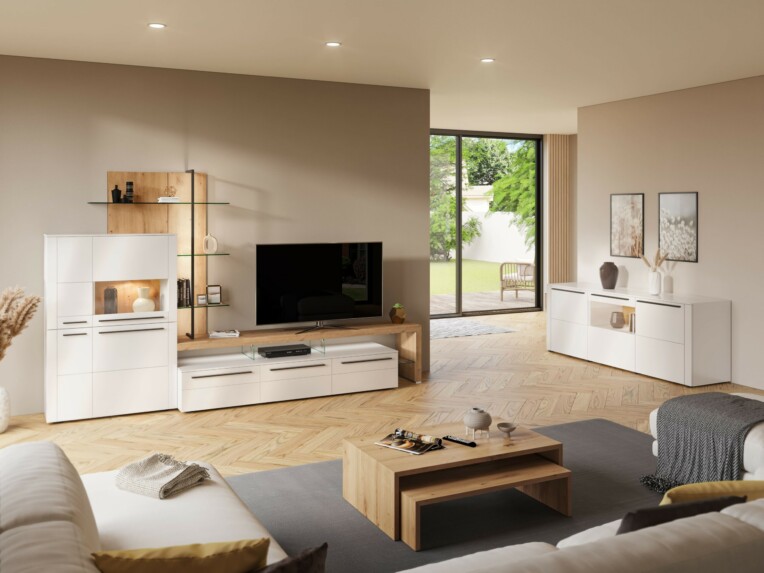 Salon contemporain avec un meuble TV blanc et bois, étagères en verre, buffet assorti et table basse en bois clair. Canapés blancs décorés de plaids et coussins créent une ambiance cocooning, face à une baie vitrée donnant sur un jardin. meubles-ambiance-cocooning-salon-salle-a-manger-le-geant-du-meuble.jpg